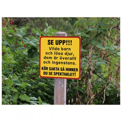 Fyrkantig skylt med text: SE UPP! Vilda barn och lösa djur, dom är överallt och ingenstans! Kör sakta så hinner du se spektaklet